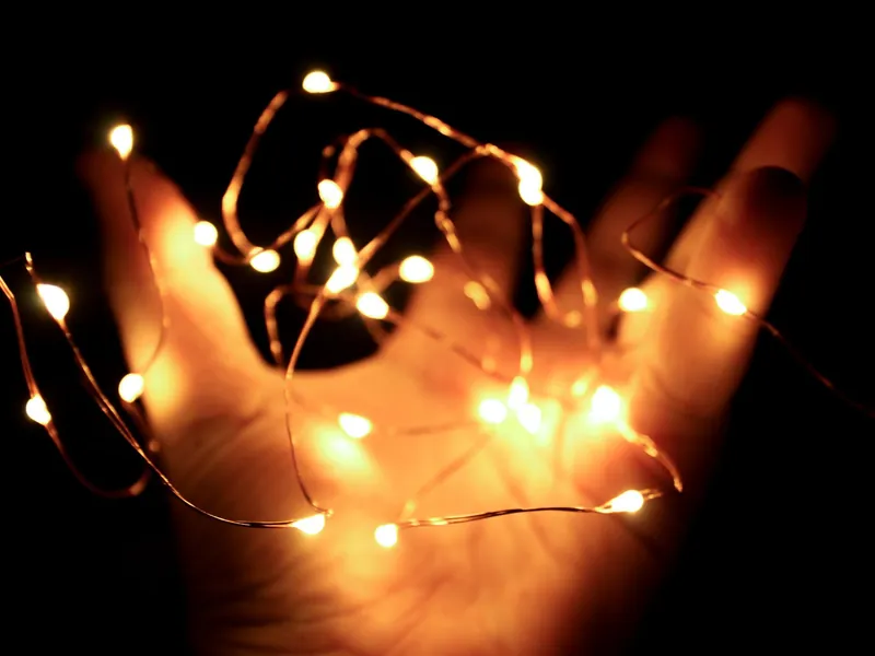 Feine Drahtlichterkette mit vielen kleinen LEDs, locker über einer geöffneten Hand