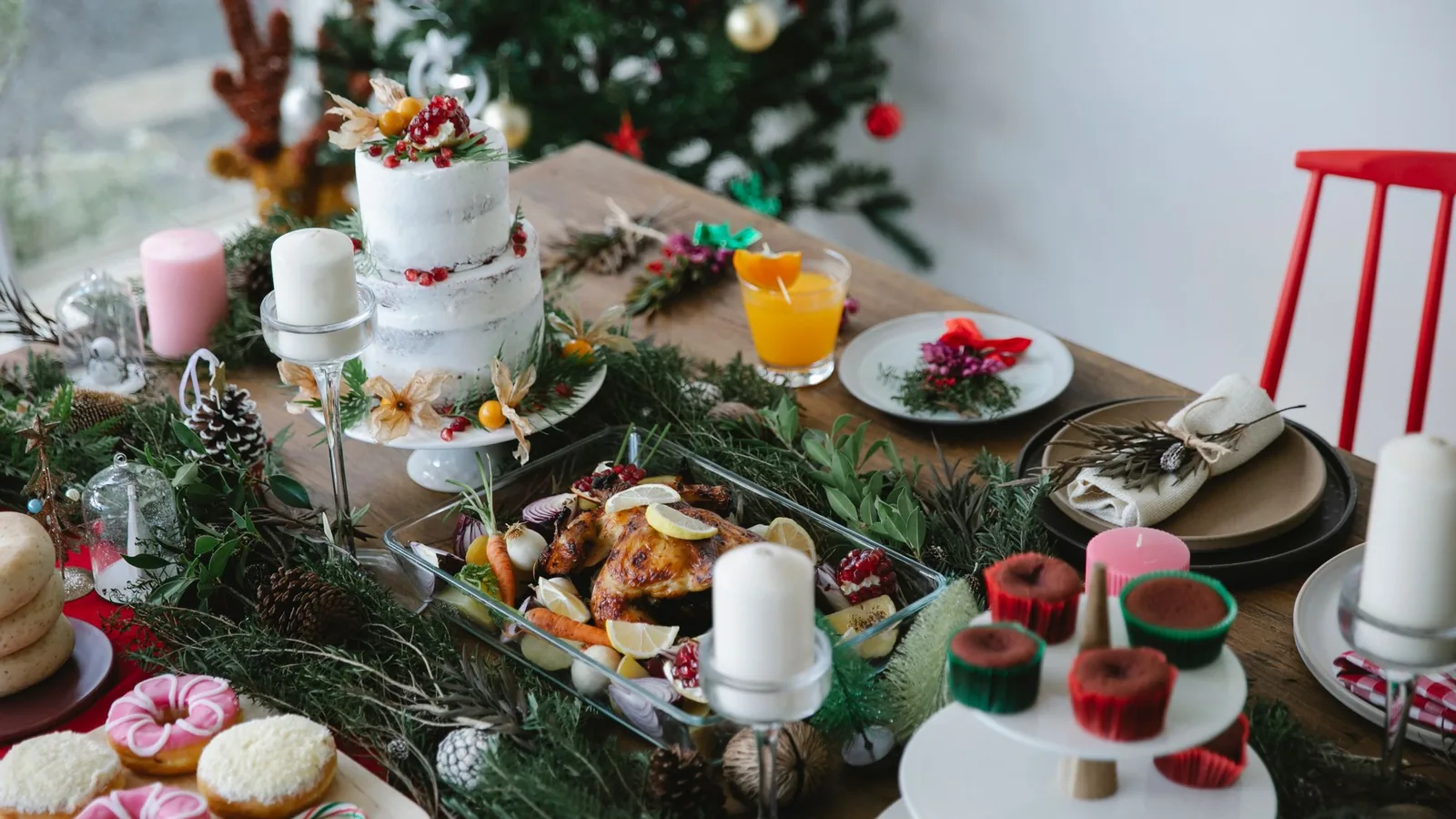 Festlich gedeckte Tafel mit Braten, Gebäck, Kerzen und Tannenzweigen in warmem Licht