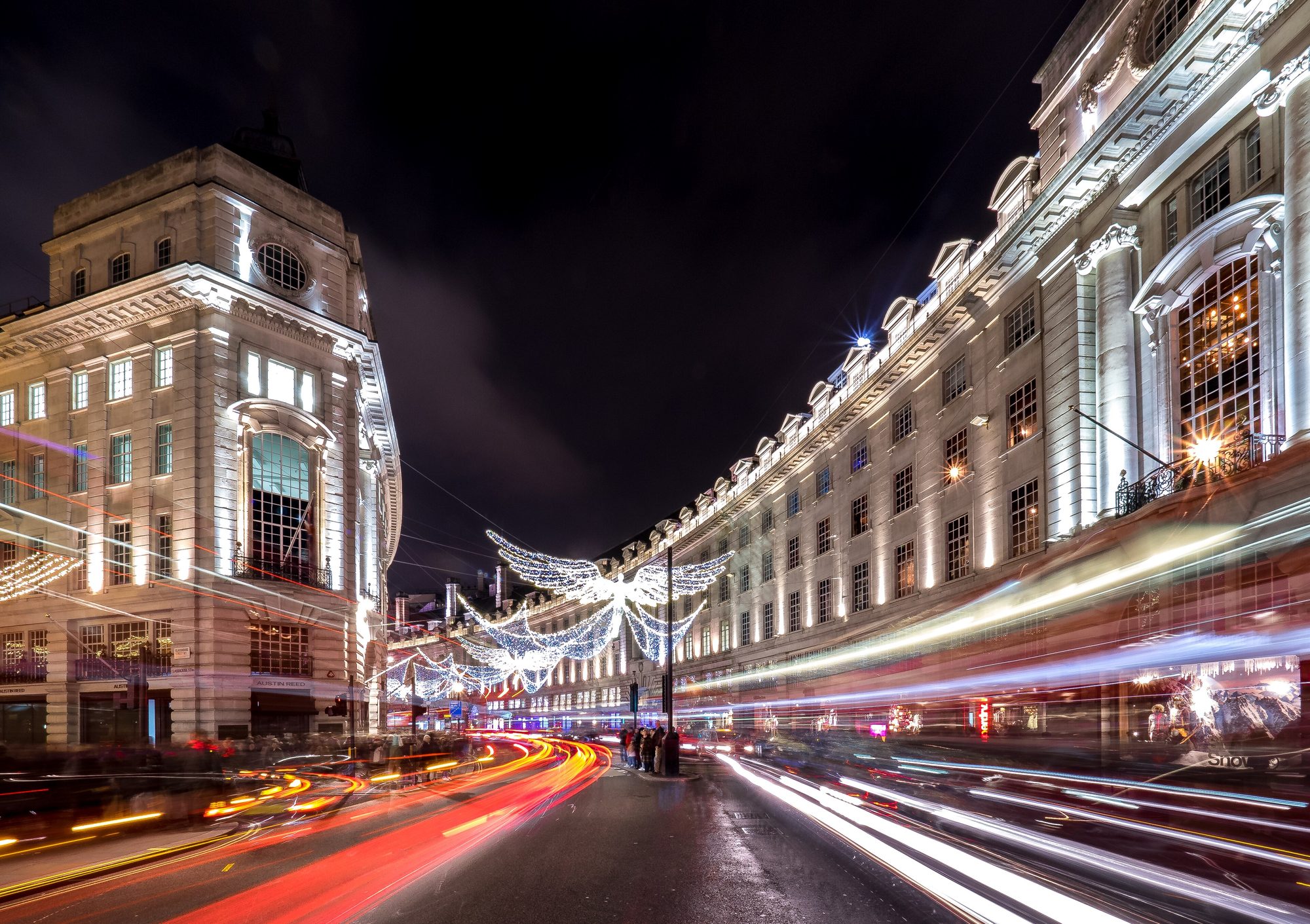 Weihnachtsbeleuchtung über der Regent Street in London bei Nacht mit Lichtspuren des Verkehrs