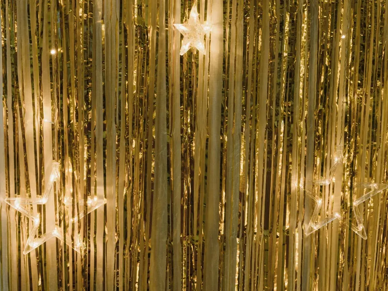 Mehrere leuchtende Sterne einer Motivlichterkette vor einem goldenen Vorhang