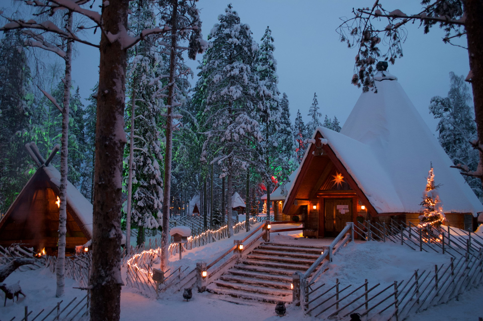 Verschneite Holzhäuser in Lappland mit warm erleuchteten Fenstern in der arktischen Dämmerung