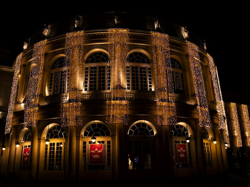 Historische Gebäudefassade bei Nacht, über mehrere Stockwerke hängen dicht gesetzte vertikale Lichtstränge herab